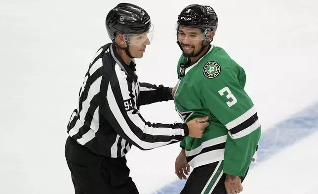 Linesman Bryan Pancich (94) holds Dallas Stars' Matt Dumba (3) back after a brief scuffle with Minnesota Wild players in the second period of a preseason NHL hockey game Wednesday, Sept. 25, 2024, in Dallas. (AP Photo/Tony Gutierrez)