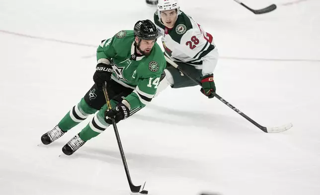 Dallas Stars left wing Jamie Benn (14) controls the puck in front of Minnesota Wild left wing Liam Ohgren (28) in the second period of a preseason NHL hockey game Wednesday, Sept. 25, 2024, in Dallas. (AP Photo/Tony Gutierrez)