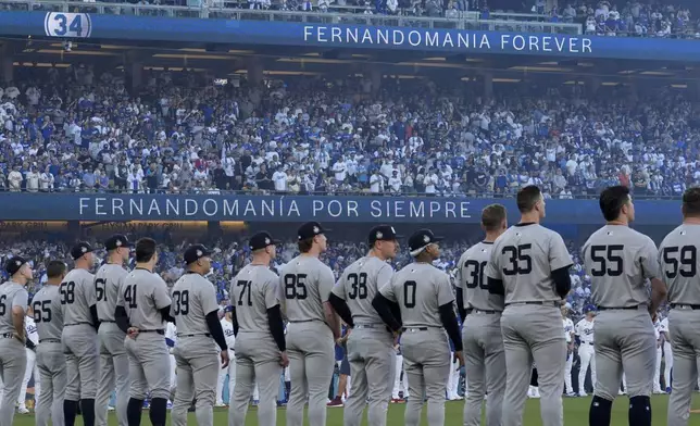 The New York Yankees stand during the moment of silence for former Dodgers pitcher Fernando Valenzuela before Game 1 of the baseball World Series against the Los Angeles Dodgers, Friday, Oct. 25, 2024, in Los Angeles. (AP Photo/Ashley Landis)