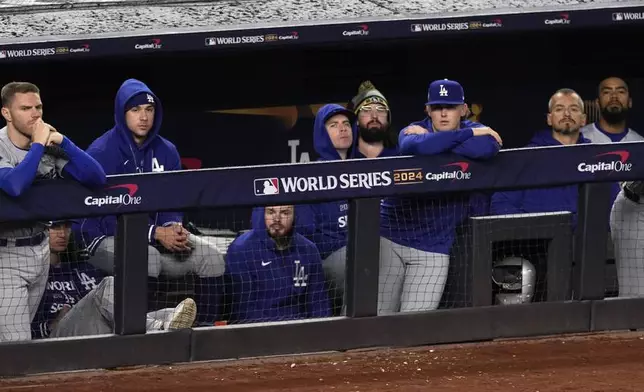 Los Angeles Dodgers players watch from the dugout during the ninth inning in Game 4 of the baseball World Series against the New York Yankees, Tuesday, Oct. 29, 2024, in New York. (AP Photo/Seth Wenig)