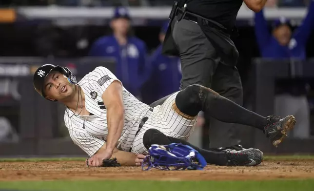 New York Yankees' Giancarlo Stanton lies on the ground after being tagged out while trying to score against the Los Angeles Dodgers during the fourth inning in Game 3 of the baseball World Series, Monday, Oct. 28, 2024, in New York. (AP Photo/Godofredo A. Vásquez)