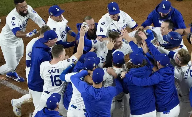 Los Angeles Dodgers' Freddie Freeman is mobbed by teammates at home plate after his walk-off grand slam home run during the 10th inning in Game 1 of the baseball World Series against the New York Yankees, Friday, Oct. 25, 2024, in Los Angeles. (AP Photo/Mark J. Terrill)