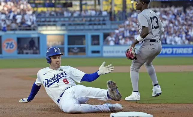 Los Angeles Dodgers' Freddie Freeman (5) slides into third base after hitting a triple against the New York Yankees during the first inning in Game 1 of the baseball World Series, Friday, Oct. 25, 2024, in Los Angeles. (AP Photo/Godofredo A. Vásquez)