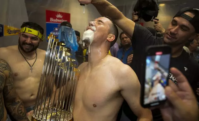 Los Angeles Dodgers pitcher Walker Buehler celebrates in the locker room after their win against the New York Yankees in Game 5 to win the baseball World Series, Thursday, Oct. 31, 2024, in New York. (AP Photo/Ashley Landis)