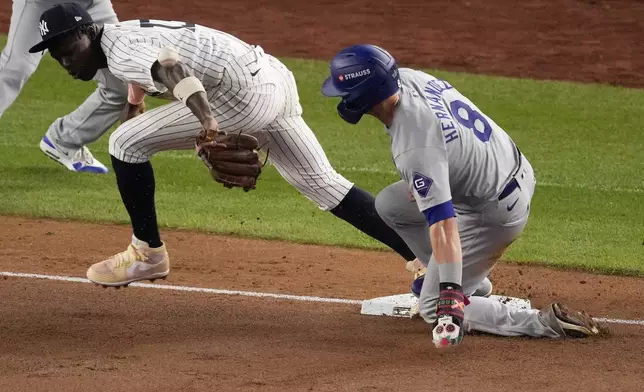 Los Angeles Dodgers' Kiké Hernández, right, is safe at third as New York Yankees third baseman Jazz Chisholm Jr. reaches for a throw from shortstop Anthony Volpe during the fifth inning in Game 5 of the baseball World Series, Wednesday, Oct. 30, 2024, in New York. Volpe was charged with a throwing error. (AP Photo/Frank Franklin II)