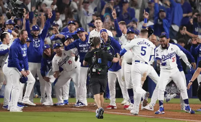 Los Angeles Dodgers' Freddie Freeman (5) is met at home plate after hitting a walk-off grand slam home run during the 10th inning in Game 1 of the baseball World Series against the New York Yankees, Friday, Oct. 25, 2024, in Los Angeles. (AP Photo/Mark J. Terrill)