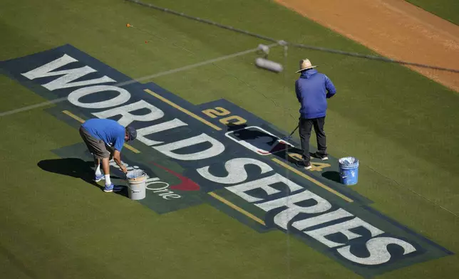 Workers prepare the field for the baseball World Series between the Los Angeles Dodgers and the New York Yankees, Thursday, Oct. 24, 2024, in Los Angeles. (AP Photo/Julio Cortez)