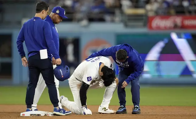 Los Angeles Dodgers' Shohei Ohtani, bottom, is helped after being injured while trying to steal second base against the New York Yankees during the seventh inning in Game 2 of the baseball World Series, Saturday, Oct. 26, 2024, in Los Angeles. (AP Photo/Godofredo A. Vásquez)