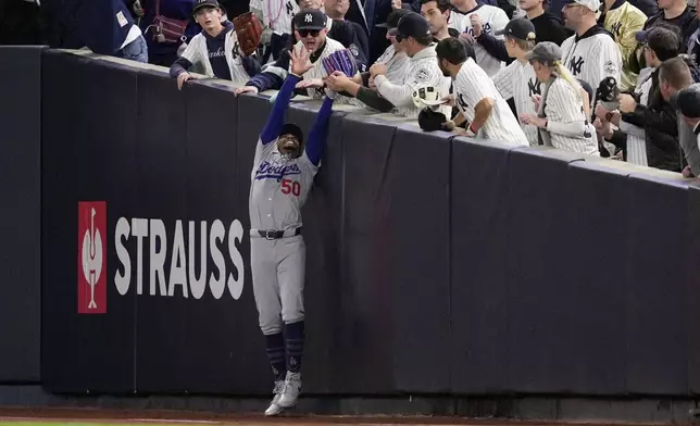 Fans interfere with a foul ball caught by Los Angeles Dodgers right fielder Mookie Betts during the first inning in Game 4 of the baseball World Series against the New York Yankees, Tuesday, Oct. 29, 2024, in New York. (AP Photo/Ashley Landis)