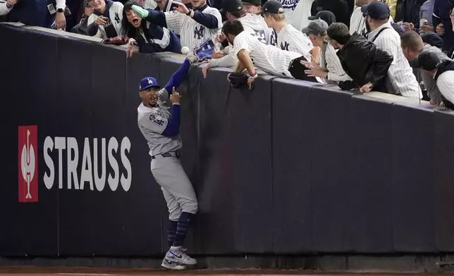 Fans interfere with a foul ball caught by Los Angeles Dodgers right fielder Mookie Betts during the first inning in Game 4 of the baseball World Series against the New York Yankees, Tuesday, Oct. 29, 2024, in New York. (AP Photo/Ashley Landis)