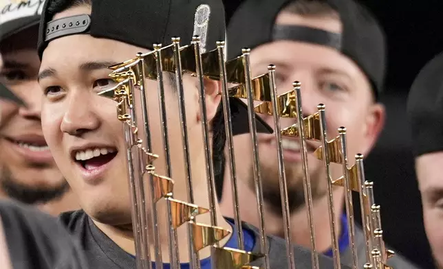 Los Angeles Dodgers' Shohei Ohtani celebrates with the trophy after their win against the New York Yankees in Game 5 to win the baseball World Series, Thursday, Oct. 31, 2024, in New York. (AP Photo/Ashley Landis)