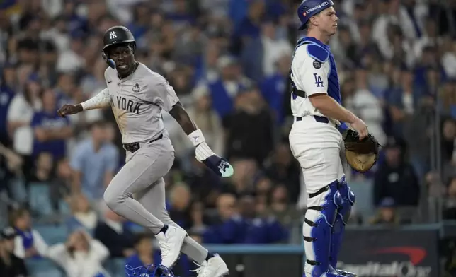 New York Yankees' Jazz Chisholm Jr. scores past Los Angeles Dodgers catcher Will Smith on a fielders choice by Anthony Volpe during the 10th inning in Game 1 of the baseball World Series, Friday, Oct. 25, 2024, in Los Angeles. (AP Photo/Ashley Landis)