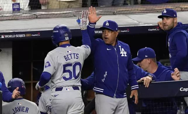 Los Angeles Dodgers' Mookie Betts (50) celebrates with manager Dave Roberts after hitting a sacrifice fly against the New York Yankees during the eighth inning in Game 5 of the baseball World Series, Wednesday, Oct. 30, 2024, in New York. (AP Photo/Seth Wenig)