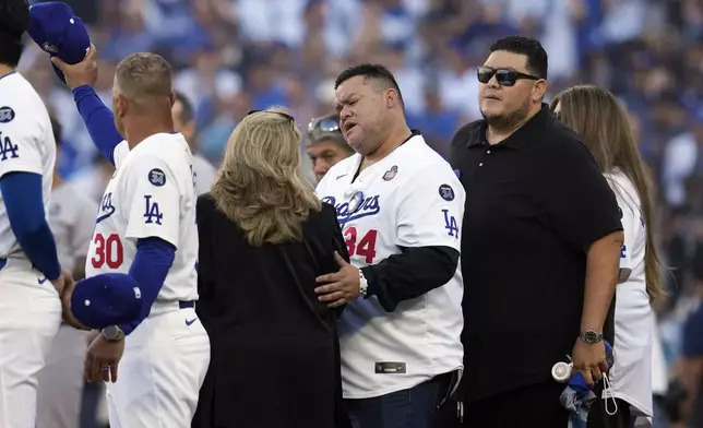 Family members of former Los Angeles Dodgers pitcher Fernando Valenzuela join the team during a moment of silence before Game 1 of the baseball World Series, Friday, Oct. 25, 2024, in Los Angeles. (AP Photo/Godofredo A. Vásquez)