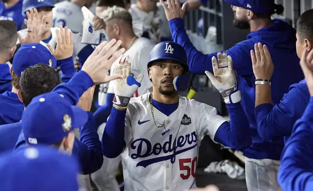 Los Angeles Dodgers' Mookie Betts (50) celebrates in the dugout after hitting a sacrifice fly against the New York Yankees during the eighth inning in Game 1 of the baseball World Series, Friday, Oct. 25, 2024, in Los Angeles. (AP Photo/Godofredo A. Vásquez)