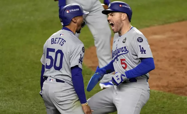 Los Angeles Dodgers' Mookie Betts (50) and Freddie Freeman (5) celebrate after scoring against the New York Yankees during the fifth inning in Game 5 of the baseball World Series, Wednesday, Oct. 30, 2024, in New York. (AP Photo/Seth Wenig)