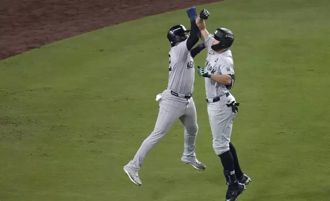 New York Yankees' Giancarlo Stanton, right, celebrates with Juan Soto after both scored on Stanton's two-run home run against the Los Angeles Dodgers during the sixth inning in Game 1 of the baseball World Series, Friday, Oct. 25, 2024, in Los Angeles. (AP Photo/Julio Cortez)