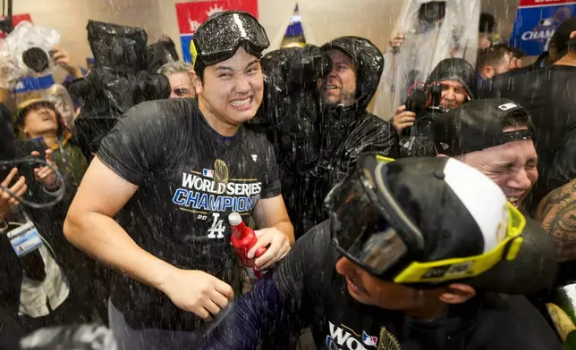 Los Angeles Dodgers' Shohei Ohtani celebrates in the locker room after their win against the New York Yankees in Game 5 to win the baseball World Series, Thursday, Oct. 31, 2024, in New York. (AP Photo/Ashley Landis)