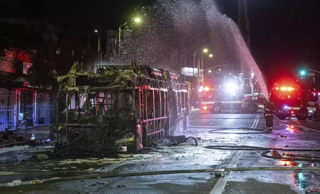 Firefighters douse water on a bus that was set on fire at Sunset and Echo Park after people gathered on the streets after the Los Angeles Dodgers defeated the New York Yankees to win the baseball World Series early Thursday, Oct. 31, 2024, in Los Angeles. (AP Photo/Ethan Swope)