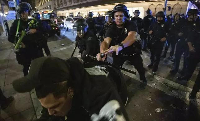 Police officers attempt to detain a man as people gather on the streets after the Los Angeles Dodgers won against the New York Yankees in the baseball World Series Wednesday, Oct. 30, 2024, in Los Angeles. (AP Photo/Ethan Swope)