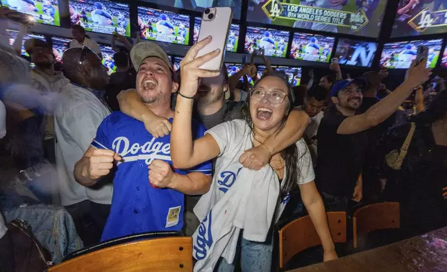 Fans celebrate after the Los Angeles Dodgers defeated the New York Yankees to win the baseball World Series Wednesday, Oct. 30, 2024, in Los Angeles. (AP Photo/Damian Dovarganes)