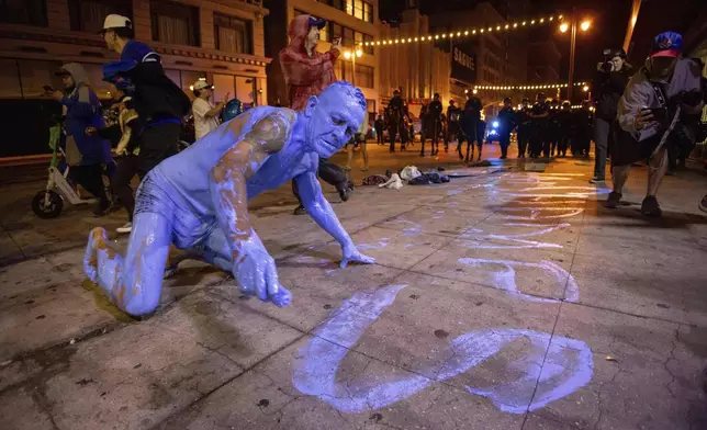 A person covered in blue paint, paints on the streets after the Los Angeles Dodgers won against the New York Yankees in the baseball World Series Wednesday, Oct. 30, 2024, in Los Angeles. (AP Photo/Ethan Swope)