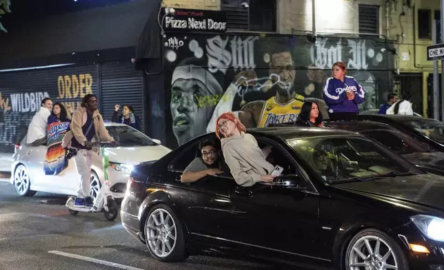 Fans celebrate on the streets after the Los Angeles Dodgers won against the New York Yankees in the baseball World Series Wednesday, Oct. 30, 2024, in downtown Los Angeles. (AP Photo/Damian Dovarganes)