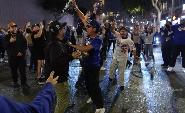 Fans celebrate on the streets after the Los Angeles Dodgers won against the New York Yankees in the baseball World Series Wednesday, Oct. 30, 2024, in downtown Los Angeles. (AP Photo/Damian Dovarganes)