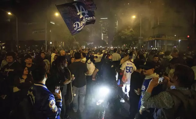 Fans celebrate on the streets after the Los Angeles Dodgers defeated the New York Yankees to win the baseball World Series Wednesday, Oct. 30, 2024, in Los Angeles. (AP Photo/Ethan Swope)