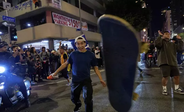 A fan looses control of his skateboard as fans celebrate on the streets after the Los Angeles Dodgers won against the New York Yankees in the baseball World Series Wednesday, Oct. 30, 2024, in Los Angeles. (AP Photo/Damian Dovarganes)