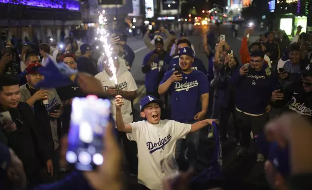 Fans celebrate on the streets after the Los Angeles Dodgers defeated the New York Yankees to win the baseball World Series Wednesday, Oct. 30, 2024, in Los Angeles. (AP Photo/Ethan Swope)