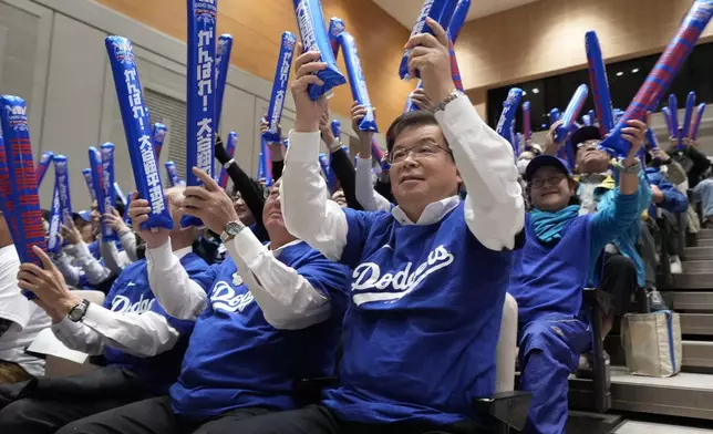 Oshu Mayor Jun Kuranari, center, and other people watch a live stream before the start of Game 3 of the baseball World Series between the Los Angeles Dodgers and the New York Yankees during a public viewing event in Oshu, northeastern Japan, the hometown of Shohei Ohtani of the Los Angeles Dodgers, Tuesday, Oct. 29, 2024. (AP Photo/Eugene Hoshiko)