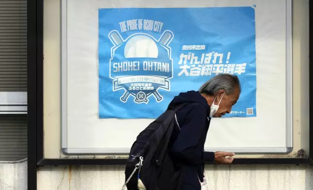 A person walks past the city's poster to support Shohei Ohtani of the Los Angeles Dodgers, near Mizusawa train station in Oshu, northeastern Japan, the hometown of Ohtani, Tuesday, Oct. 29, 2024. (AP Photo/Eugene Hoshiko)