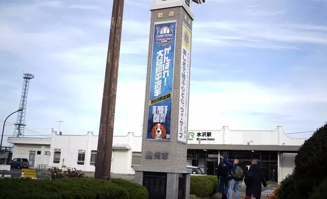 Visitors walk past a banner to support Shohei Ohtani of the Los Angeles Dodgers, near Mizusawa train station in Oshu, northeastern Japan, the hometown of Ohtani, Tuesday, Oct. 29, 2024. (AP Photo/Eugene Hoshiko)