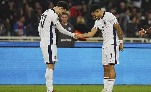 England's Curtis Jones, left, shakes hands as celebrates with his teammate Morgan Gibbs-White, after scoring the third goal against Greece during the UEFA Nations League Group F soccer match between Greece and England at Olympic Stadium in Athens, Thursday, Nov. 14, 2024. (AP Photo/Petros Giannakouris)