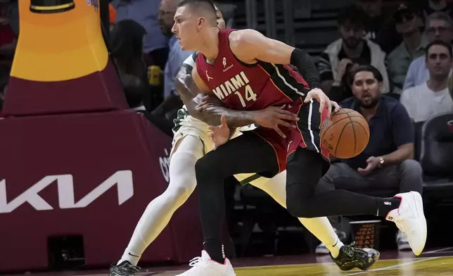 Miami Heat guard Tyler Herro (14) loses control of the ball as Milwaukee Bucks guard Damian Lillard, behind, defends during the first half of an Emirates NBA Cup basketball game, Tuesday, Nov. 26, 2024, in Miami. (AP Photo/Lynne Sladky)