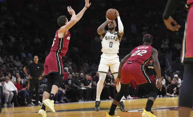 Milwaukee Bucks guard Damian Lillard (0) shoots over Miami Heat forward Duncan Robinson, left, and forward Jimmy Butler (22) during the first half of an Emirates NBA Cup basketball game, Tuesday, Nov. 26, 2024, in Miami. (AP Photo/Lynne Sladky)