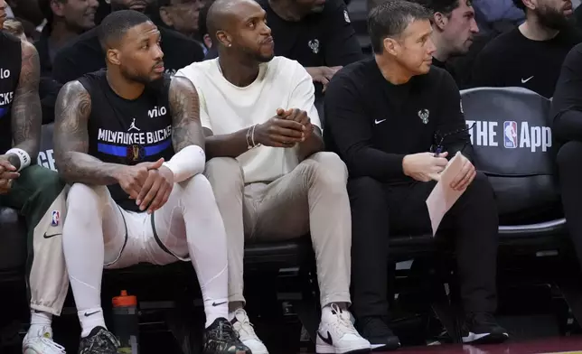 Milwaukee Bucks forward Khris Middleton, center, sits next to guard Damian Lillard, left, during the first half of an Emirates NBA Cup basketball game against the Miami Heat, Tuesday, Nov. 26, 2024, in Miami. (AP Photo/Lynne Sladky)