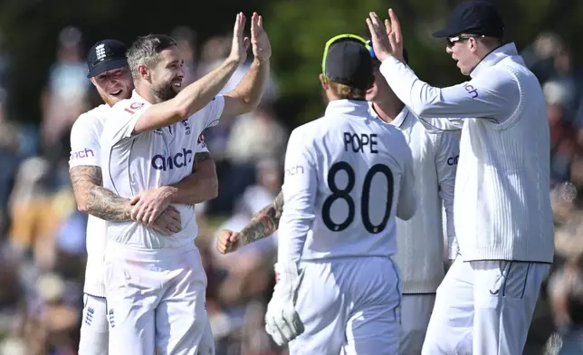 England bowler Chris Woakes, second left, celebrates with teammates after taking the wicket of New Zealand's Kane Williamson during play on the third day of the first cricket test between England and New Zealand at Hagley Oval in Christchurch, New Zealand, Saturday, Nov. 30, 2024. (Andrew Cornaga/Photosport via AP)