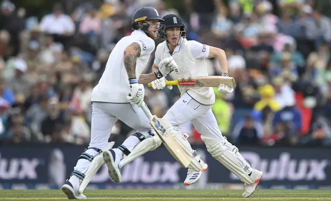 England's Harry Brook, right, and teammate Ben Stokes run between the wickets during play on the third day of the first cricket test between England and New Zealand at Hagley Oval in Christchurch, New Zealand, Saturday, Nov. 30, 2024.(John Davidson/Photosport via AP)