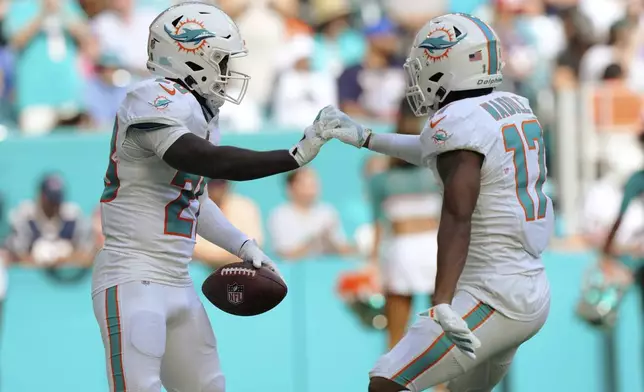 Miami Dolphins running back De'Von Achane (28) celebrates his touchdown with wide receiver Jaylen Waddle (17) during the first half of an NFL football game against the New England Patriots, Sunday, Nov. 24, 2024, in Miami Gardens, Fla. (AP Photo/Wilfredo Lee)