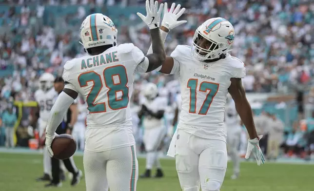 Miami Dolphins running back De'Von Achane (28) celebrates his touchdown with wide receiver Jaylen Waddle (17) during the first half of an NFL football game against the New England Patriots, Sunday, Nov. 24, 2024, in Miami Gardens, Fla. (AP Photo/Lynne Sladky)