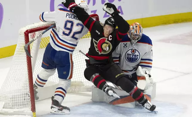 Ottawa Senators left wing Brady Tkachuk crashes into the net with Edmonton Oilers right wing Vasily Podkolzin and goaltender Stuart Skinner after the play had been stopped during the first period of an NHL hockey game, Tuesday, Nov. 19, 2024 in Ottawa, Ontario. (Adrian Wyld/The Canadian Press via AP)