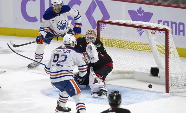 Edmonton Oilers defenseman Evan Bouchard (2) watches the puck bounce around the back of the net after scoring on Ottawa Senators goaltender Linus Ullmark as the Oilers' Vasily Podkolzin looks on during the first period of an NHL hockey game, Tuesday, Nov. 19, 2024 in Ottawa, Ontario. (Adrian Wyld/The Canadian Press via AP)