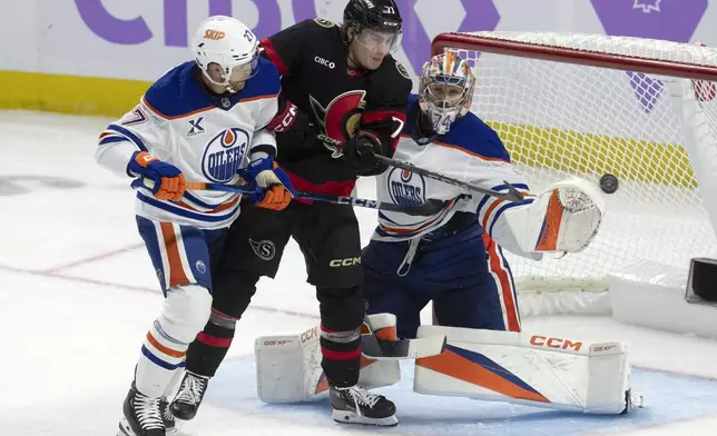 Ottawa Senators center Ridly Greig (71) tries to tip the puck past Edmonton Oilers goaltender Stuart Skinner under pressure from Oilers' Brett Kulak (27) during the second period of an NHL hockey game in Ottawa, Tuesday, Nov. 19, 2024. (Adrian Wyld/The Canadian Press via AP)