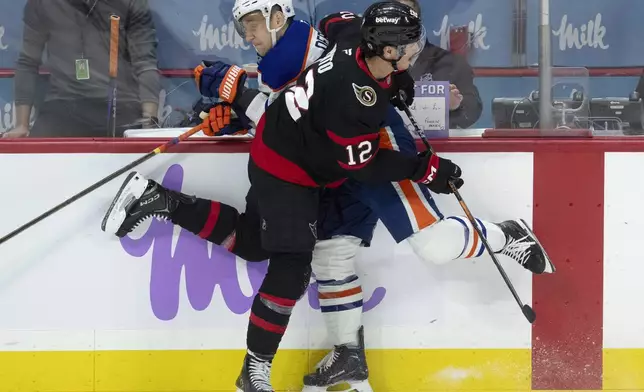 Ottawa Senators center Shane Pinto (12) runs into Edmonton Oilers defenseman Travis Dermott along the boards during the first period of an NHL hockey game, Tuesday, Nov. 19, 2024 in Ottawa, Ontario. (Adrian Wyld/The Canadian Press via AP)