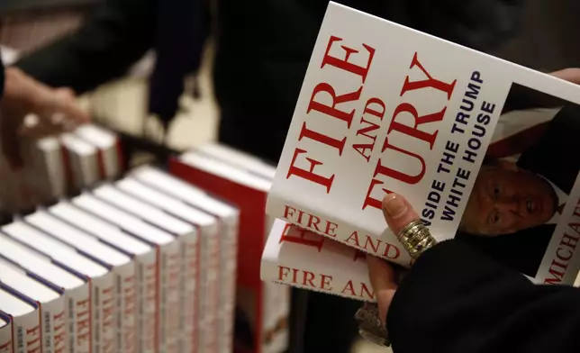 FILE - A customer looks at a copy of Michael Wolff's "Fire and Fury: Inside the Trump White House" as they go on sale at a bookshop, in London, Tuesday, Jan. 9, 2018. (AP Photo/Alastair Grant, File)