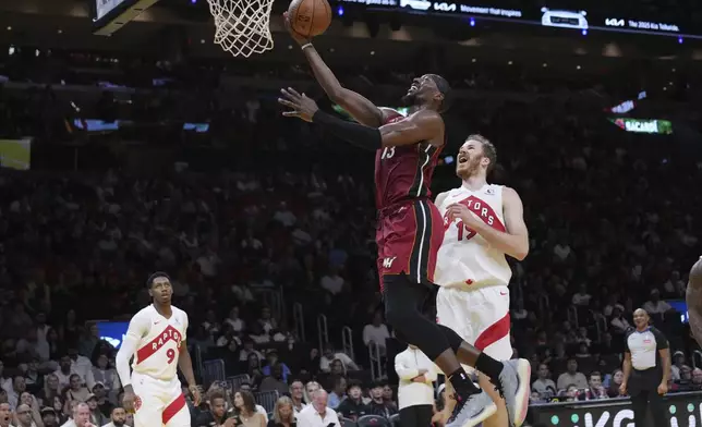Miami Heat center Bam Adebayo (13) goes to the basket over Toronto Raptors center Jakob Poeltl (19) during the first half of an Emirates NBA Cup basketball game, Friday, Nov. 29, 2024, in Miami. (AP Photo/Lynne Sladky)