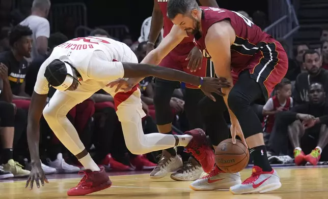 Toronto Raptors forward Chris Boucher, left, loses control of the ball as Miami Heat forward Kevin Love, right, defends during the first half of an Emirates NBA Cup basketball game, Friday, Nov. 29, 2024, in Miami. (AP Photo/Lynne Sladky)