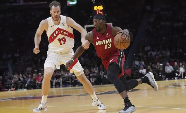 Miami Heat center Bam Adebayo (13) drives to the basket as Toronto Raptors center Jakob Poeltl (19) defends during the first half of an Emirates NBA Cup basketball game, Friday, Nov. 29, 2024, in Miami. (AP Photo/Lynne Sladky)